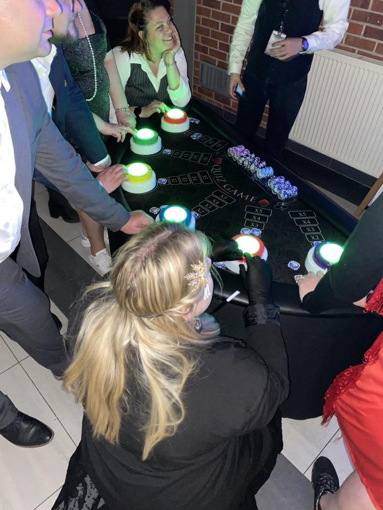 Invités élégants autour de la table Quiz Game avec buzzers verts lumineux Quiz Game Table de Casino - Animation team building événement entreprise